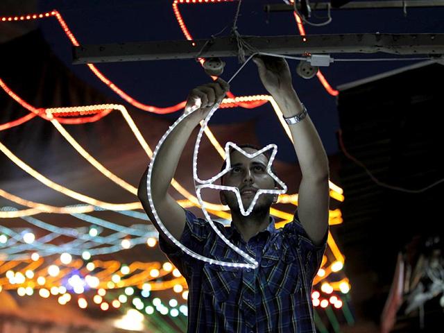 A Palestinian man decorates his shop with fairy lights near the entrance of the Al-Aqsa mosque compound, in the old city of Jerusalem (AFP Photo)