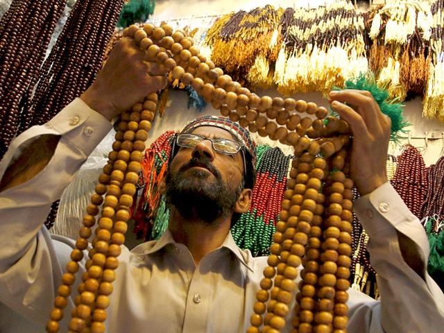A prayer beads salesman looks at oversized prayer beads at his shop at a market in Peshawar, Pakistan (Reuters Photo)