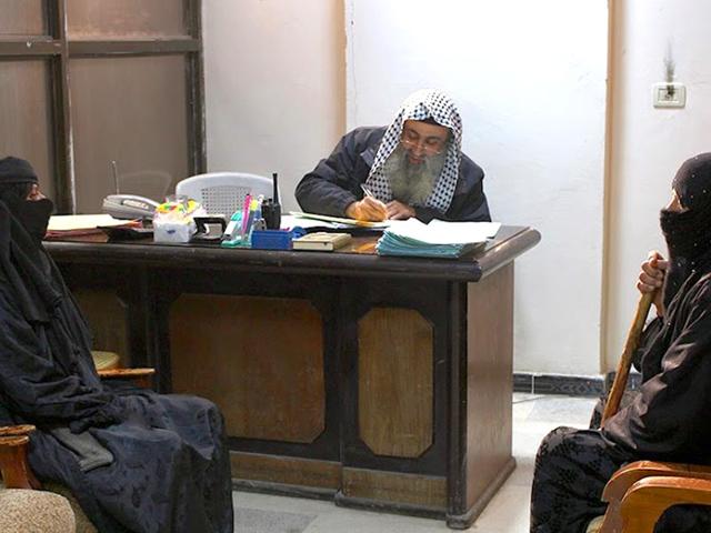 In-this-photo-released-by-a-militant-website-which-has-been-verified-and-is-consistent-with-other-AP-reporting-two-women-sit-in-the-office-of-an-Islamic-State-group-judge-at-an-Islamic-court-in-al-Tabqa-town-in-Raqqa-City-Syria-Militant-website-via-AP