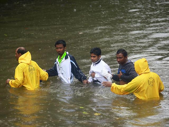 People are helped by police personnel as they cross a flooded road during heavy rains in Mumbai (Reuters Photo)