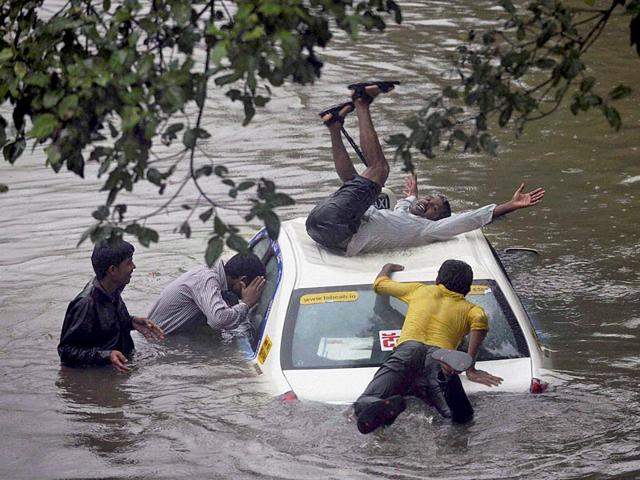 A vehicle stuck in rain water at a road as boys having fun after heavy shower in Mumbai (PTI Photo)