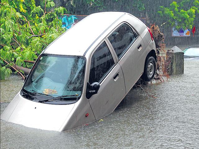 A car gets lifted off the ground after a tree near which it was parked was uprooted at King's Circle in Mumbai following hevay rains in Mumbai. (Vijayanand Gupta/HT Photo)