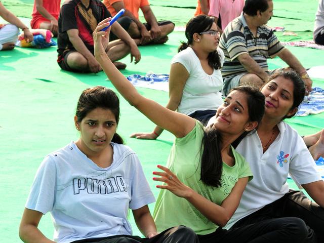 Girls taking a selfie while performing yoga at Exhibition Ground Sector 34 in Chandigarh on Sunday. (Keshav Singh/HT Photo)