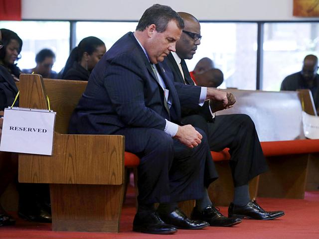 New Jersey governor Chris Christie, left, and Dwayne D Warren, mayor of Orange, NJ, hold hands during a service at St. Matthew African Methodist Episcopal Church. (AP Photo)