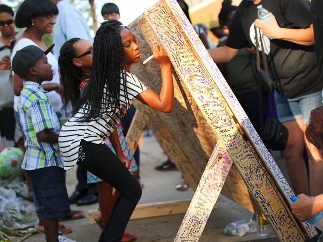 People leave messages of hope and encouragement on a large canvas titled "Charleston United" in front of the historic Emanuel African American Methodist Church. (AFP Photo)