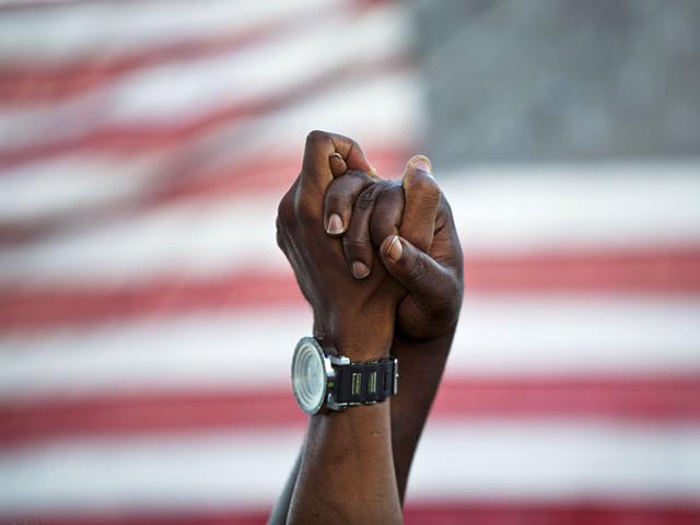 People join hands against the backdrop of an American flag as thousands of marchers meet in the middle of Charleston's main bridge in a show of unity after nine black church parishioners were gunned down during a Bible study. (AP Photo)
