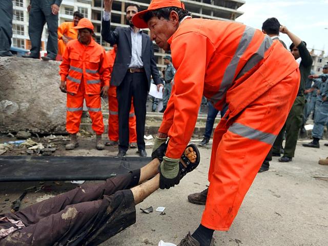 An Afghan municipality worker carries the dead body of a Taliban attacker after clashes with security forces in front of the Parliament, in Kabul. (AP Photo)