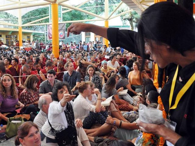 A Tibetan boy presenting silver coin to devotees on the occasion of Dalai Lama's 80th birthday celebration at Tsuglagkhang Temple in Mcleodganj on Monday. Shyam Sharma/HT