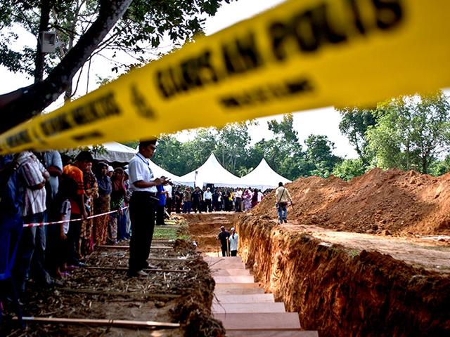A Malaysian Muslim man looks on as he stands near a pit during the re-burial of remains believed to be those of ethnic Rohingya found at human-trafficking camps (AFP Photo)