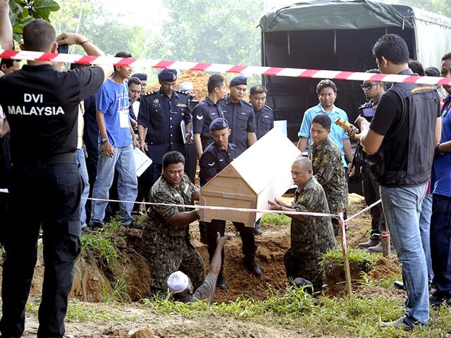 Malaysian police carries a coffin containing the remains of a Rohingya migrant for a mass burial ceremony (AP Photo)