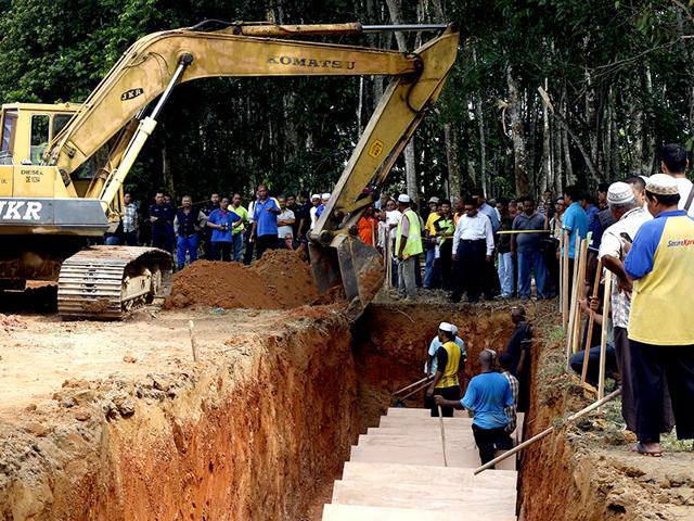 Earth is used to fill a mass grave with the remains of unidentified Rohingya people found at a traffickers camp in Wang Kelian last month, at a cemetery near Alor Setar, Malaysia (Reuters Photo)