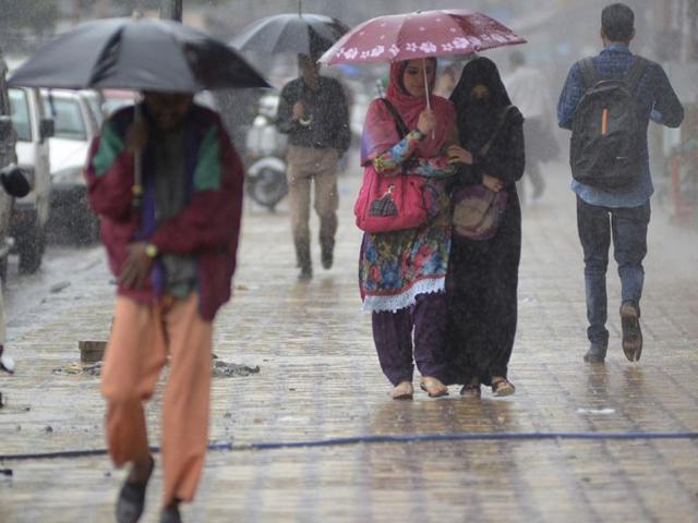 People shield themselves from the rain with umbrellas in Srinagar. Waseem Andrabi/ HT