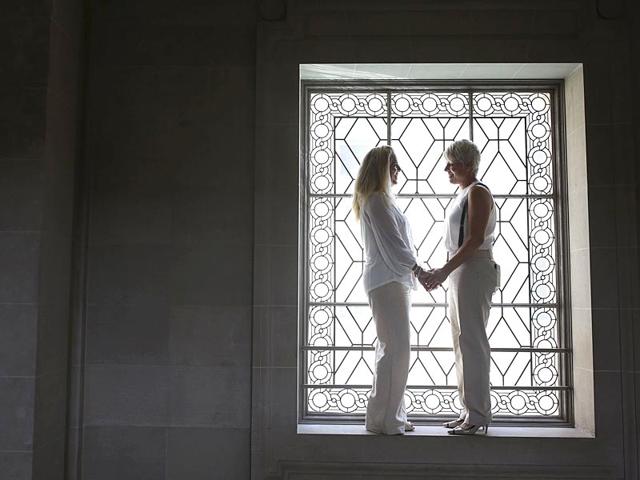 Stacy Wood (L) and her wife Michele Barr pause between wedding photos at San Francisco City Hall after getting married in San Francisco, California. The Supreme Court ruled 5-4 that the Constitution's guarantees of due process and equal protection under the law mean that states cannot ban same-sex marriages. (Reuters)