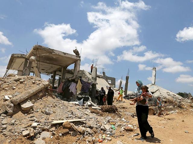 A-Palestinian-woman-holds-her-daughter-as-she-walks-past-the-ruins-of-houses-that-witnesses-said-were-destroyed-by-Israeli-shelling-during-a-50-day-war-last-summer-Reuters-File-Photo