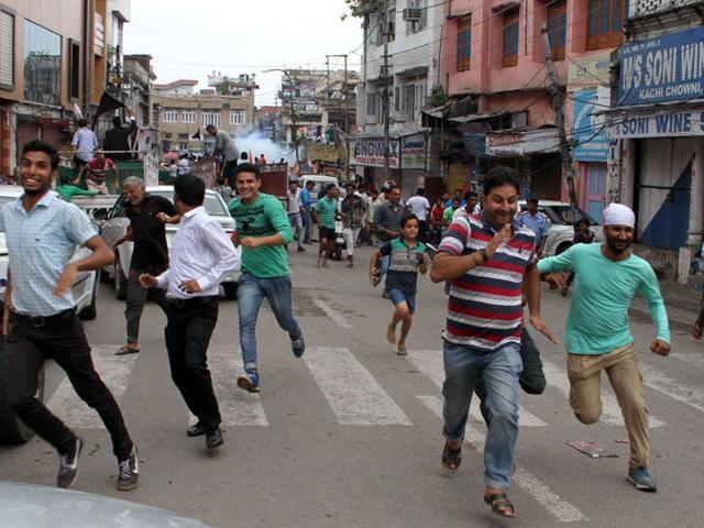 People running after a tear gas shell is fired by police in Jammu.(HT File)
