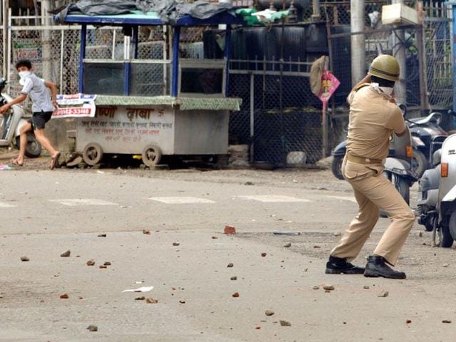 A boy runs to take shelter as the policeman throws a smoke shell in his direction (Nitin Kanotra/HT)