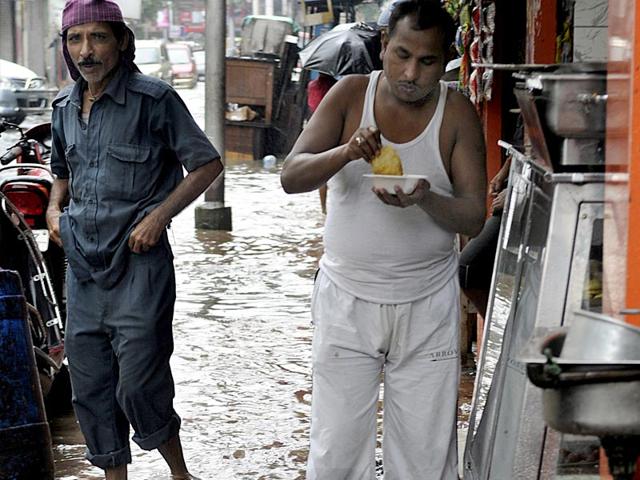 A man having snacks while standing on a flooded road in central Kolkata. (Ashok Nath Dey/ HT Photo)