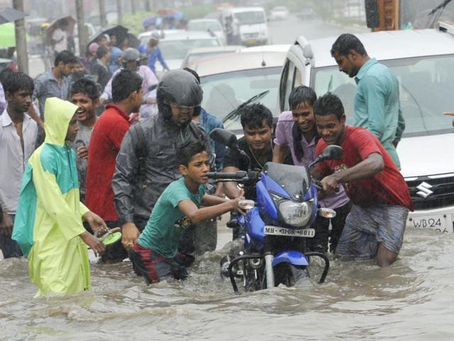 People push a bike stuck on watelogged streets at Rajarhat. (Subhankar Chakraborty/HT Photo)