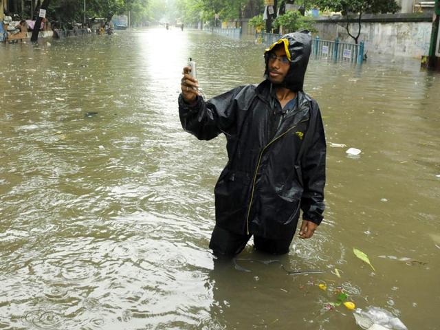 A boy takes a selfie on a flooded street at Amherst Street in central Kolkata. (Samir Jana/HT Photo)
