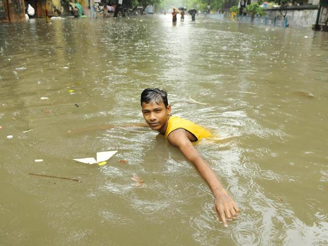 A boy swims in a pool of rainwater at Amherst Street on Saturday. (Samir Jana/HT Photo)