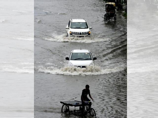 Rickshaws and cars wade through a waterlogged road at Rajarhat. (Subhankar Chakraborty/HT Photo)