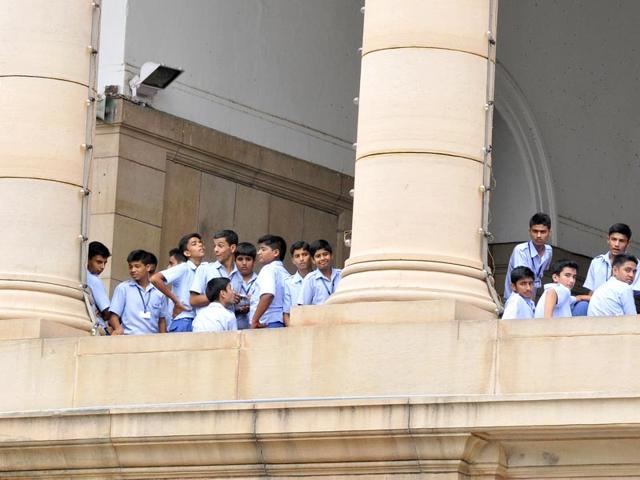 School students look at the Congress members as they protest aginst NDA govenment near Gandhi Statue at Parliament complex. (Sonu Mehta/HT Photo)