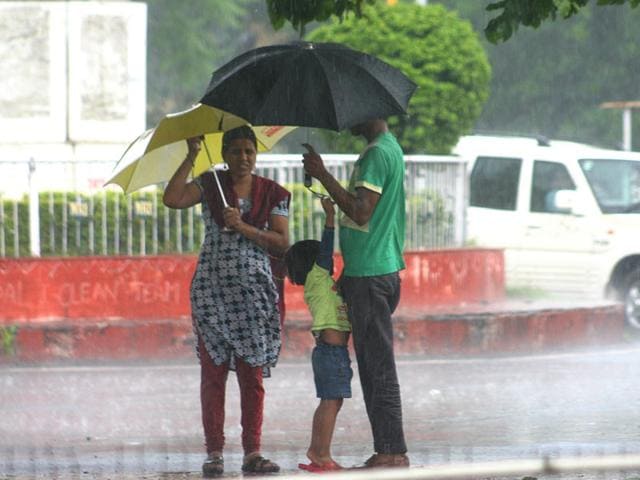 Residents protect them from showers in Bhopal on Tuesday.(Bidesh Manna/HT photo)