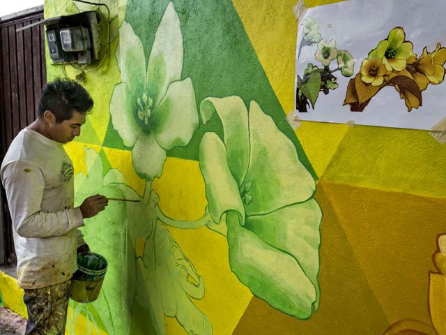 An artist paints a mural on one of the streets of the hill 'Las Palmitas'. A Mexican artists' collective German Crew painted a giant mural across houses, with the help of residents, to transform their crumbling walls into vibrant artwork. (AFP Photo)