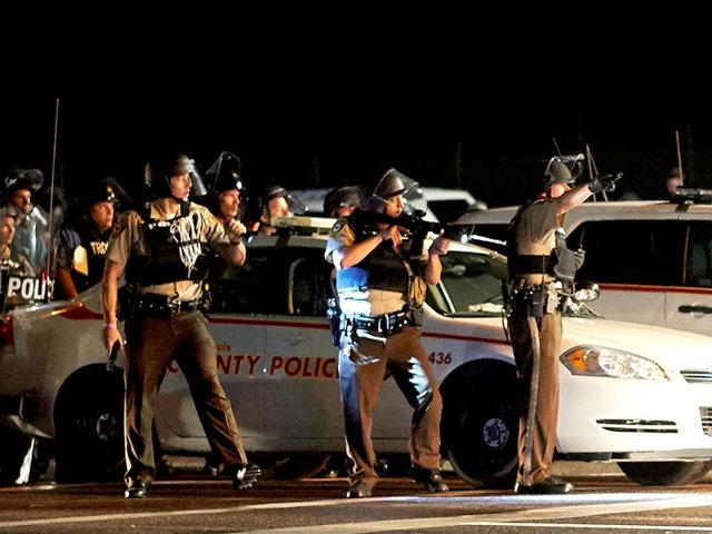 A-St-Louis-County-police-officer-directs-an-oncoming-car-looking-to-evacuate-the-area-after-a-police-involved-shooting-during-a-protest-march-on-August-9-2015-on-West-Florissant-Avenue-in-Ferguson-AFP-Photo