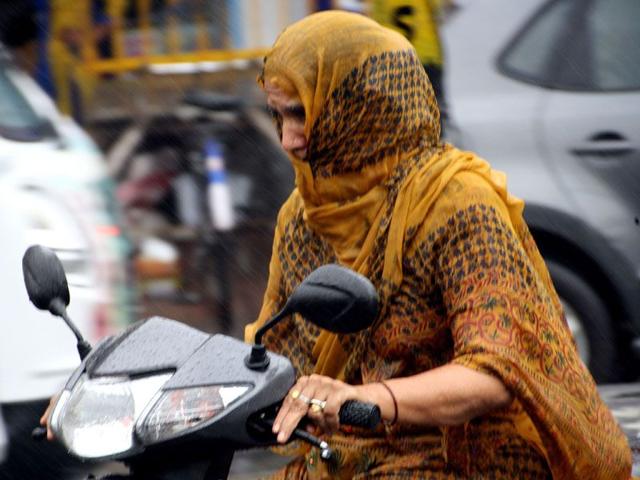 Commuters trying to cope with thunder-showers which lashed Rohtak town on Saturday. Manoj Dhaka/HT