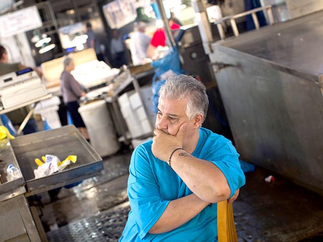 A shopkeeper waits for customers at a fishing market in central Athens, Wednesday, July 15, 2015. Greece's Parliament votes Wednesday on an 85-billion-euro bailout deal meant to prevent the country's economy from collapsing. (AP Photo)