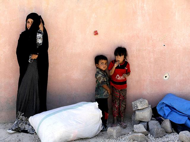 A refugee from the northern Syrian town of Tel Abyad and her children wait while spending the day in Akcakale, Turkey, in this June 18, 2015 file picture. (Reuters) A refugee from the northern Syrian town of Tel Abyad and her children wait while spending the day in Akcakale, Turkey, in this June 18, 2015 file picture. (Reuters)