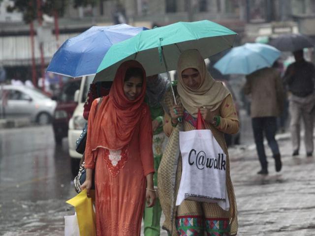 Girls protect themselves with an umbrella as it rained in Kashmir valley on Thursday. Wasim Andrabi/HT