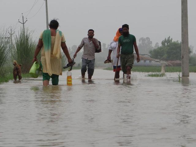 Residents of Mand area walking through water-filled roads on Saturday. Parampreet Singh Narula/HT