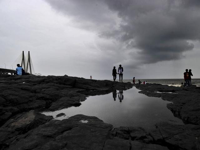 Dark clouds loom over the city as people take a stroll at Bandra, in Mumbai. (Vidya Subramanian/HT photo)