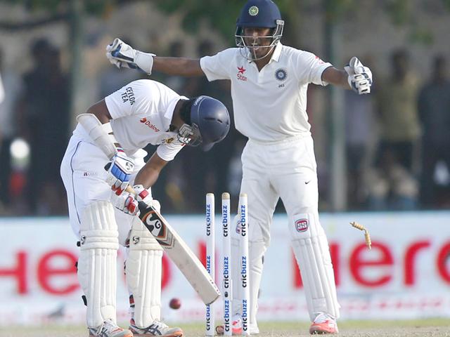 Sri Lanka's Dimuth Karunaratne (L) is bowled out by India's Ravichandran Ashwin (not pictured) next to India's wicketkeeper Wriddhiman Saha during the second day of their first test cricket match in Galle. REUTERS/Dinuka Liyanawatte