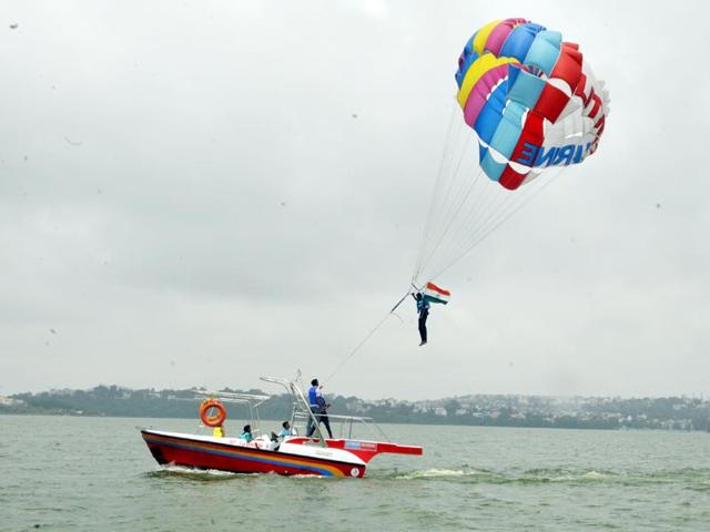 To make the most of the pleasant weather ahead of the Independence Day, a youth enjoys water parasailing holding a national flag at Boat Club in Bhopal. (HT Photo/Praveen Bajpai)