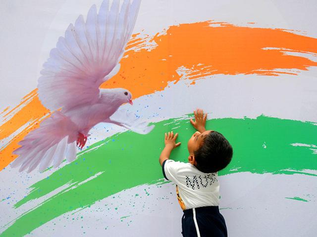A kid plays against the backdrop of the Indian Tricolour on Independence Day at Goregoan, in Mumbai. (Photo: Sanjay Solanki)