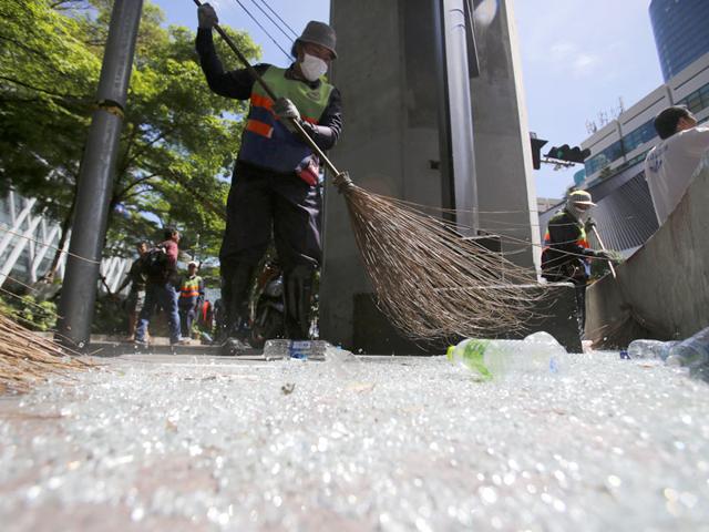 Workers sweep broken glass near the Erawan Shrine at Rajprasong intersection in Bangkok, Thailand, Tuesday, Aug. 18, 2015, the morning after an explosion. Police combed through shattered glass and other debris Tuesday from a bomb blast in central Bangkok, trying to determine who set off the most devastating single attack in the capital's recent history. (AP Photo/Sakchai Lalit)