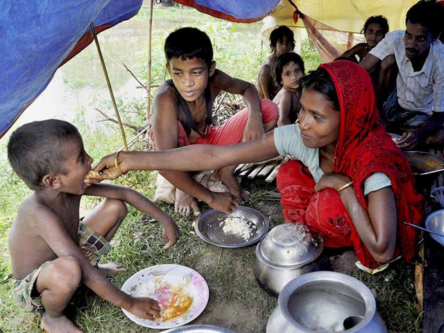A mother feeds her children at a relief camp after the family's home was submerged in floods in Bura Bure area of Morigaon district of Assam. (PTI Photo)