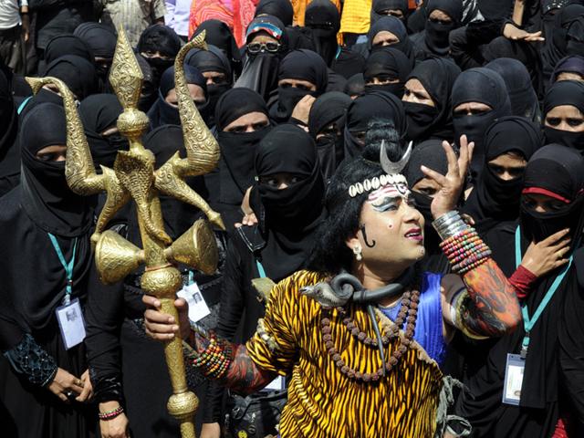 A man dressed as Lord Shiva dances at the launch of an all-religion kanwar yatra as burqa-clad Muslim women look on, in Indore on Monday. (Shankar Mourya/HT Photo)