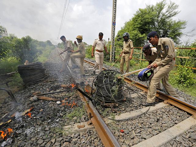 Policemen remove cables from a railway track which were set on fire by the protesters in Ahmedabad. India deployed paramilitary forces and imposed a curfew in the western state of Gujarat on Wednesday after violence broke out at a protest led by a powerful clan to demand more government jobs and college places. (Reuters Photo)