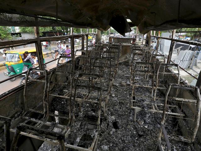 People are seen through a damaged bus that was burnt in the clashes between the police and protesters in Ahmedabad. Three people have reportedly died in widespread violence across Gujarat, with leader Hardik Patel vowing to intensify the agitation. (Reuters Photo)