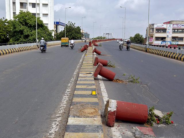 Vehicles travel past flower pots installed on a road divider which were damaged in the clashes between the police and protesters in Ahmedabad. Curfew was imposed in various parts of Gujarat as the Patidar community intensified its agitation. (Reuters Photo)