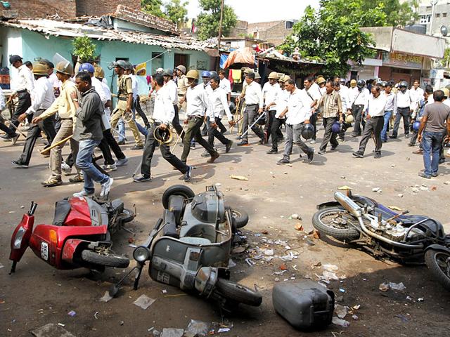 Commuters ride their motocycles next to the wreckage of a bus that was burnt during clashes between the police and protesters in Ahmedabad. (Reuters Photo) Commuters ride their motocycles next to the wreckage of a bus that was burnt during clashes between the police and protesters in Ahmedabad. (Reuters Photo)