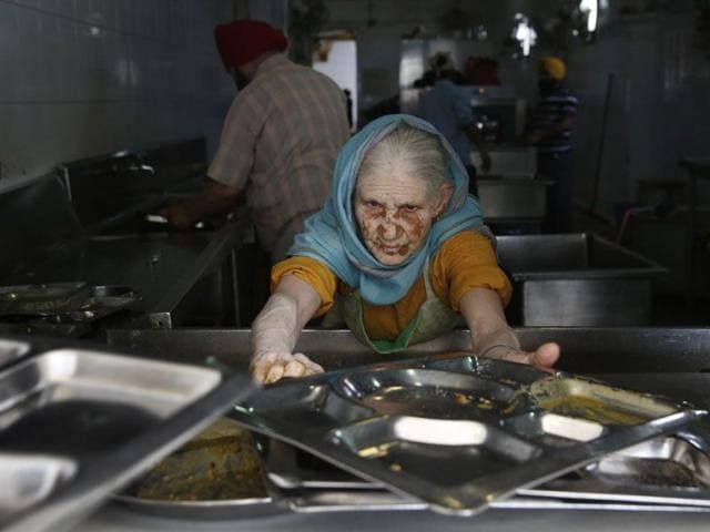A woman collects used plates from devotees to clean after they finish eating langar at the Bangla Sahib Gurdwara in New Delhi.(AP Photo/Manish Swarup) A woman collects used plates from devotees to clean after they finish eating langar at the Bangla Sahib Gurdwara in New Delhi.(AP Photo/Manish Swarup)