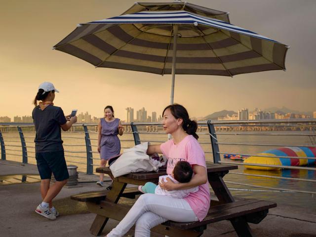 A woman cradles a child as she sits before the Han River and the city skyline in Seoul. (AFP Photo)