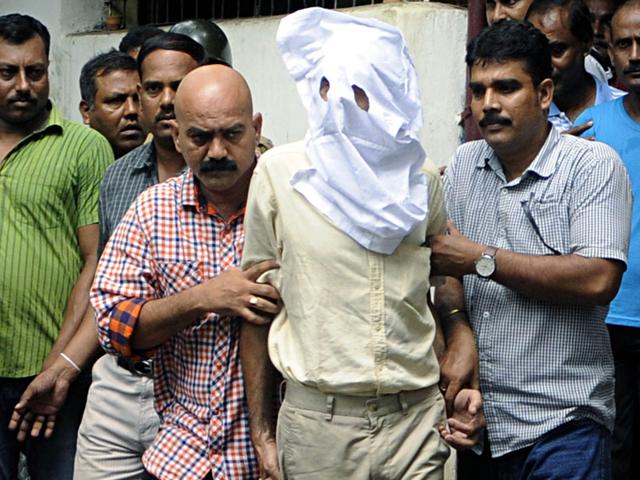 Sanjeev Khanna, face covered, a Kolkata-based businessman being taken to a court on Thursday. (Subhendu Ghosh/HT Photo)