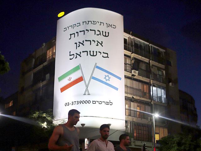 People walk past a large billboard depicting both national flags of Israel (right) and Iran reading 'The Iranian embassy in Israel will open soon' in central Tel Aviv on August 27, 2015. The giant poster announcing the opening of an Iranian embassy in Tel Aviv was revealed to be a PR campaign for an Israeli comic film "Atomic Falafel" about the Iranian nuclear threat. AFP Photo People walk past a large billboard depicting both national flags of Israel (right) and Iran reading 'The Iranian embassy in Israel will open soon' in central Tel Aviv on August 27, 2015. The giant poster announcing the opening of an Iranian embassy in Tel Aviv was revealed to be a PR campaign for an Israeli comic film "Atomic Falafel" about the Iranian nuclear threat. AFP Photo
