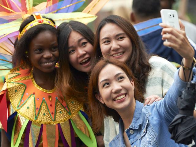 A group of women take a selfie with a performer on the first day of the Notting Hill Carnival in London on August 30, 2015. (AFP)